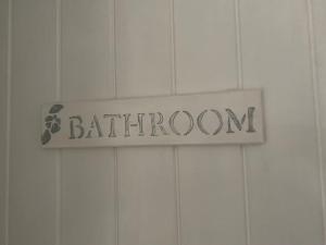a sign for a bathroom on a white tiled wall at Idyllic holiday near Abersoch in Mynytho