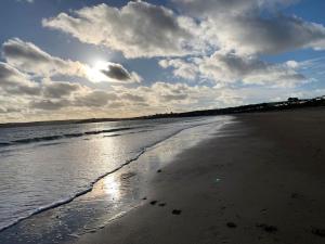 a beach with the sun reflecting on the water at Idyllic holiday near Abersoch in Mynytho