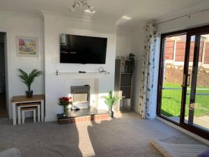 a living room with a fireplace and a flat screen tv at Idyllic holiday near Abersoch in Mynytho