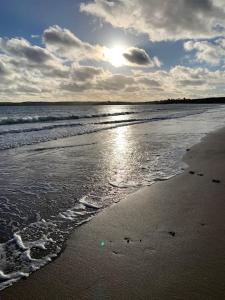 a beach with the sun shining on the water at Idyllic holiday near Abersoch in Mynytho