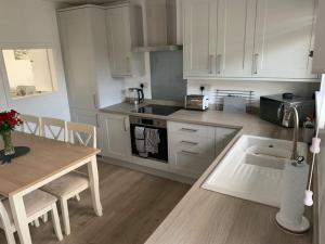 a kitchen with white cabinets and a wooden table and a table and a tableablish at Idyllic holiday near Abersoch in Mynytho