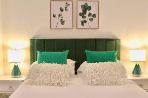 1 cama con 2 almohadas verdes y 2 lámparas en Luxury - Pet Friendly 3bd, 3ba South End Condo en Boston