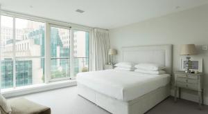 a white bedroom with a bed and large windows at Luxury Panoramic 3 bed with private terrace in London