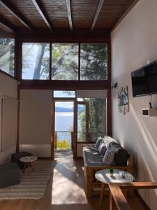 uma sala de estar com um sofá e algumas janelas em Bosque al Lago em San Carlos de Bariloche