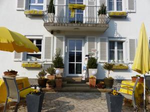 ein weißes Haus mit einem Balkon sowie Tischen und Stühlen in der Unterkunft Haus Marija M in Badenweiler