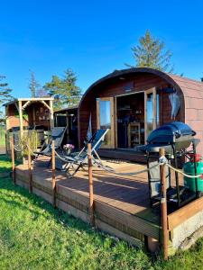 a round house with a deck and chairs in front of it at FINN VILLAGE - Loch Lomond Sunset Glamping Pod - Private Ofuro HOT TUB in Drymen