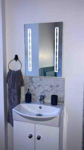 ein Badezimmer mit einem weißen Waschbecken und einem Spiegel in der Unterkunft First floor apartment in Stratton, Bude in Stratton