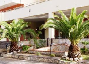 two palm trees in front of a building at Hotel Le Dune in Licola