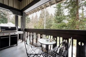 a porch with a table and chairs and a grill at Amazing Village Location with PRIVATE Hot Tub in Whistler