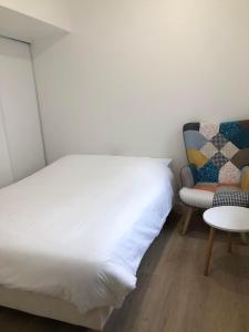 1 dormitorio con 1 cama, 1 silla y 1 mesa en F2 équipé, 15mn de Paris, parking, climatisation, en Bourg-la-Reine