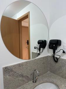 espejo sobre un lavabo en el baño en Studio Felicittá piscina cozinha academia en Juiz de Fora