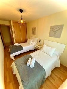 Habitación de hotel con 2 camas y lámpara de araña. en TuristHome Greco, en Sarria