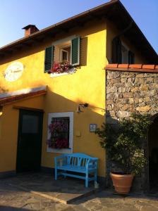 une maison jaune avec un banc bleu devant elle dans l'établissement Sostio a Levante, à Framura