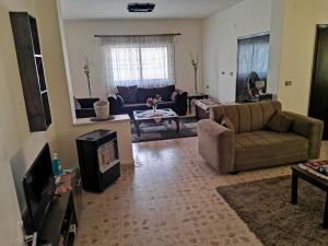 uma sala de estar com dois sofás e uma televisão em Alice & Andrew Apt. Few Steps to Madaba Old City Center em Madaba