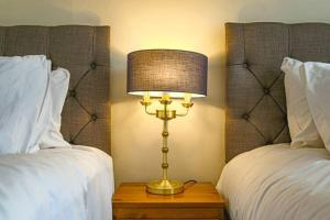 a lamp sitting on a table next to two beds at Lowndes House - Close to City Centre - Garden, Free Parking and Smart TV by Yoko Property in Milton Keynes