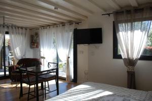 Schlafzimmer mit einem Bett, einem Tisch und einem TV in der Unterkunft Gîte Le Logis Vallat Bas in Fuveau