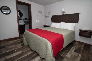 une chambre avec un grand lit avec une couverture rouge dans l'établissement Motel Au Bord de l'Eau, à Rimouski