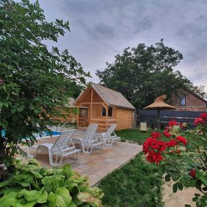 a deck with chairs and a cabin in the yard at Village Story kuća za odmor Plavna 