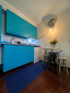 a blue kitchen with a table and a clock on the wall at Anchor House in Câmara de Lobos