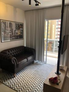 a living room with a leather couch and a television at Studio Luxo Completo Independência 915- São Mateus in Juiz de Fora