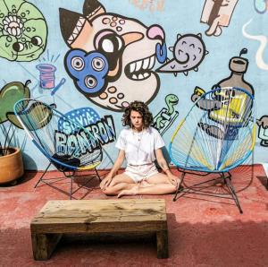 una mujer sentada frente a una pared con dos sillas en Gente de Más Hostel, en Puebla