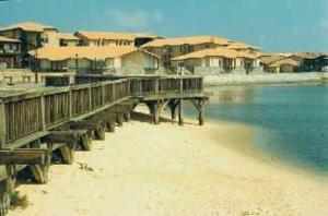 a dock on a beach with houses in the water at Appartements à côté Lac Marin de Port d'Albret in Vieux-Boucau-les-Bains