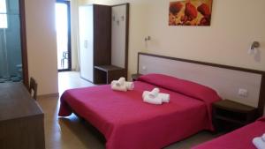 a bedroom with a red bed with two white towels on it at B&B Hotel Helios in Uggiano la Chiesa