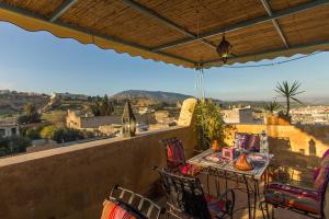 a balcony with a table and chairs and a view at Riad Noujoum Medina in Fez