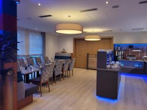 a dining room with tables and chairs and a kitchen at Hotel-Restaurant Kämper Superior in Bad Zwischenahn