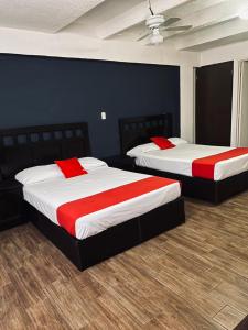 two beds in a bedroom with red and white sheets at Hotel Halley in León