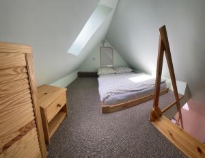 ein kleines Schlafzimmer im Dachgeschoss mit einem Bett und einer Kommode in der Unterkunft Nad Strumykiem 2 in Duszniki-Zdrój