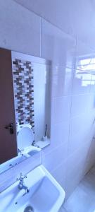 a white bathroom with a sink and a mirror at The Purple Gem Airbnb -South B- Oak South Apartments in Nairobi