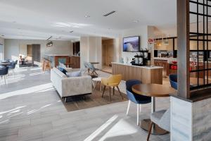 a lobby with chairs and tables and a kitchen at TownePlace Suites Columbus Hilliard in Hilliard