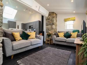 a living room with two couches and a stone wall at The Dairy in Helston