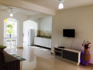 a living room with a refrigerator and a tv on the wall at Villa Vanuza in Santa Cruz Cabrália