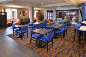 a dining room with tables and blue chairs at Courtyard Atlanta Suwanee in Suwanee