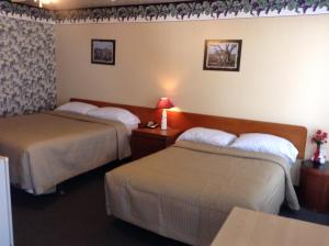 a hotel room with two beds and a table at Motel Rive Du Lac in Saint-Zotique