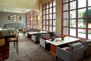 Atlanta Marriott Suites Midtown في أتلانتا: مطعم بطاولات وكراسي ونوافذ