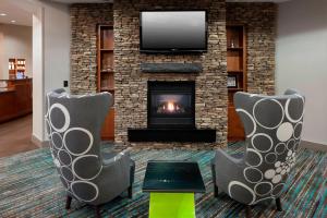 sala de estar con 2 sillas y chimenea en Residence Inn by Marriott Hattiesburg, en Hattiesburg