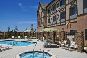una piscina en un hotel con sillas y sombrillas en Fairfield Inn & Suites by Marriott Selma Kingsburg, en Kingsburg