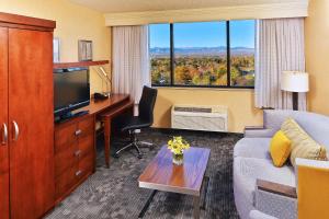 Habitación de hotel con sofá, escritorio y TV en Courtyard by Marriott Denver Cherry Creek en Denver