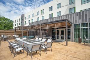 un patio avec des tables et des chaises en face d'un bâtiment dans l'établissement Courtyard by Marriott Charleston-North Charleston, à Charleston