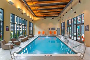 a pool in a hotel lobby with chairs and a swimming pool at Aloft Columbus Easton in Columbus