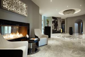 a living room with a fireplace and white chairs at Hotel am Steinplatz, Autograph Collection in Berlin