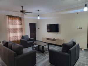 VaQ Apartments في Spintex: غرفة معيشة مع كراسي وتلفزيون بشاشة مسطحة