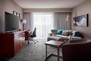 a hotel room with a couch and a desk and a television at Courtyard by Marriott Denver Airport in Denver