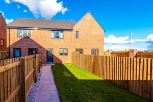 a brick house with a wooden fence and grass at Videl Homes in Manchester