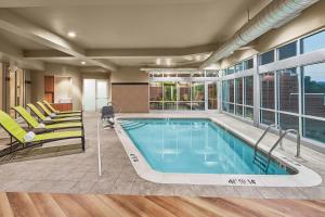 een zwembad in een huis met stoelen en een zwembad bij SpringHill Suites by Marriott Roanoke in Roanoke