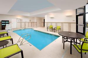 una piscina con mesas y sillas en una habitación de hotel en SpringHill Suites by Marriott Albuquerque North/Journal Center, en Alameda