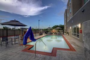 a swimming pool with a blue umbrella and a building at TownePlace Suites by Marriott Houston Hobby Airport in Houston